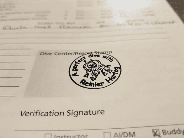 My personalized stamp in my wife's logbook. Stamp that says 'A perfect dive with Reinier Hartog' in a PADI logbook.